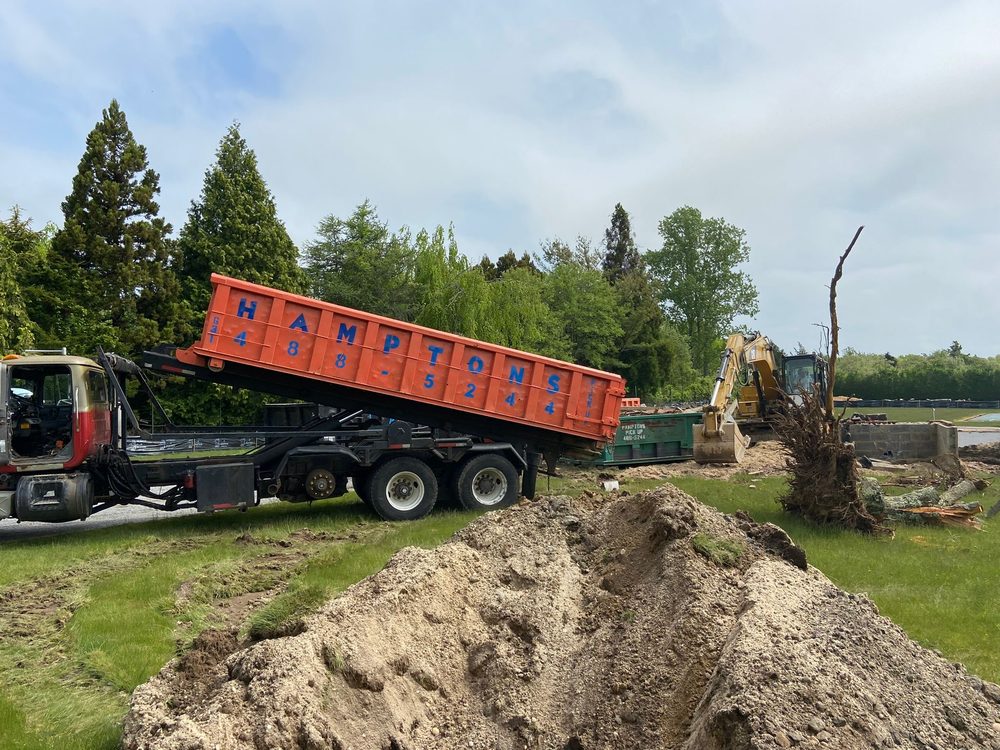 A Hamptons Pick Up truck unloading construction debris at a build site