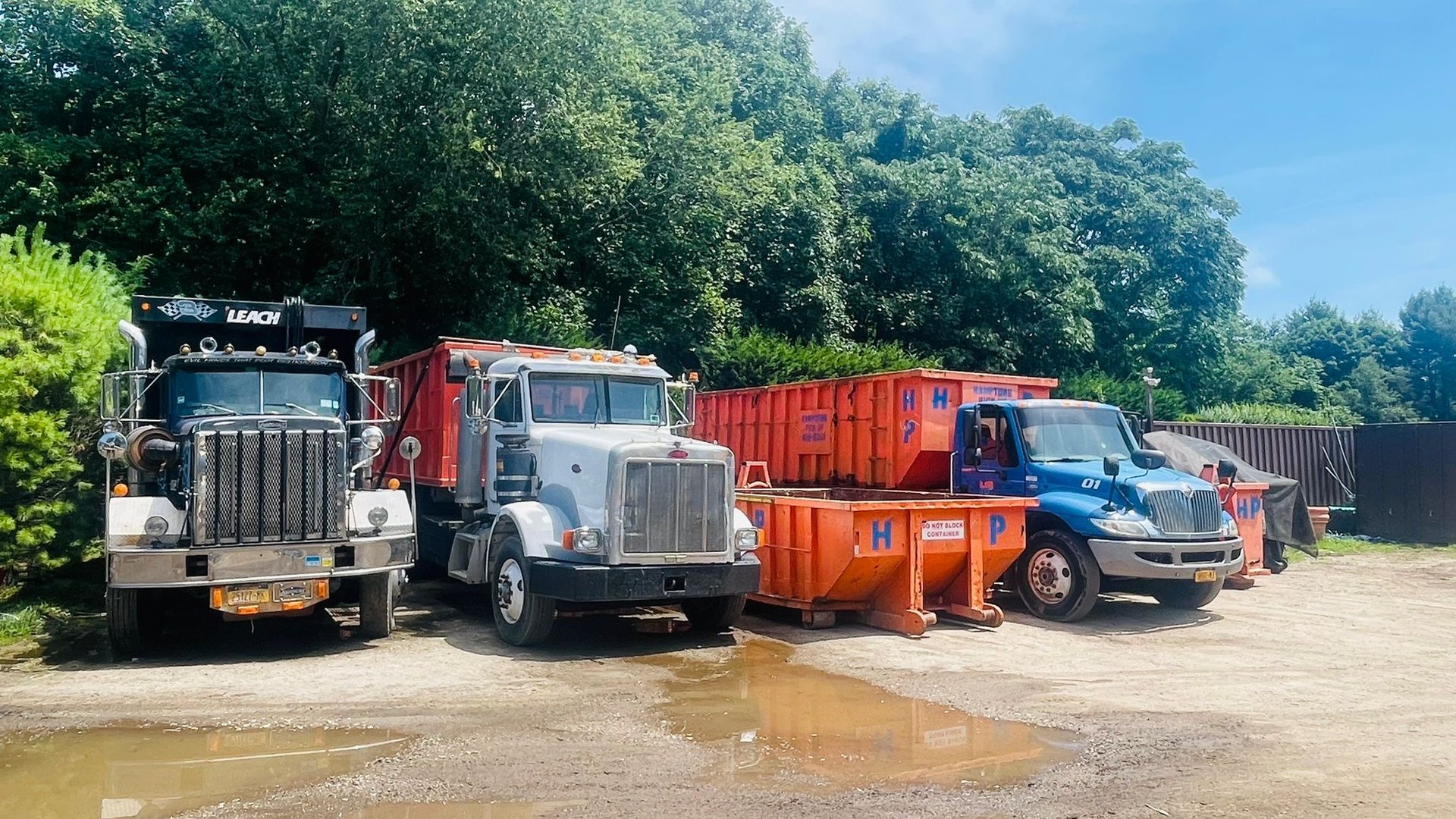 The Hamptons Pick Up fleet of trucks and orange roll-off containers at the Aquebogue yard
