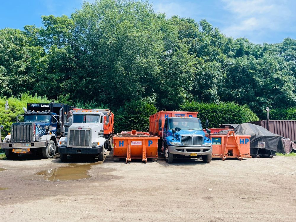 Hamptons Pick Up orange roll-off containers and trucks at the yard